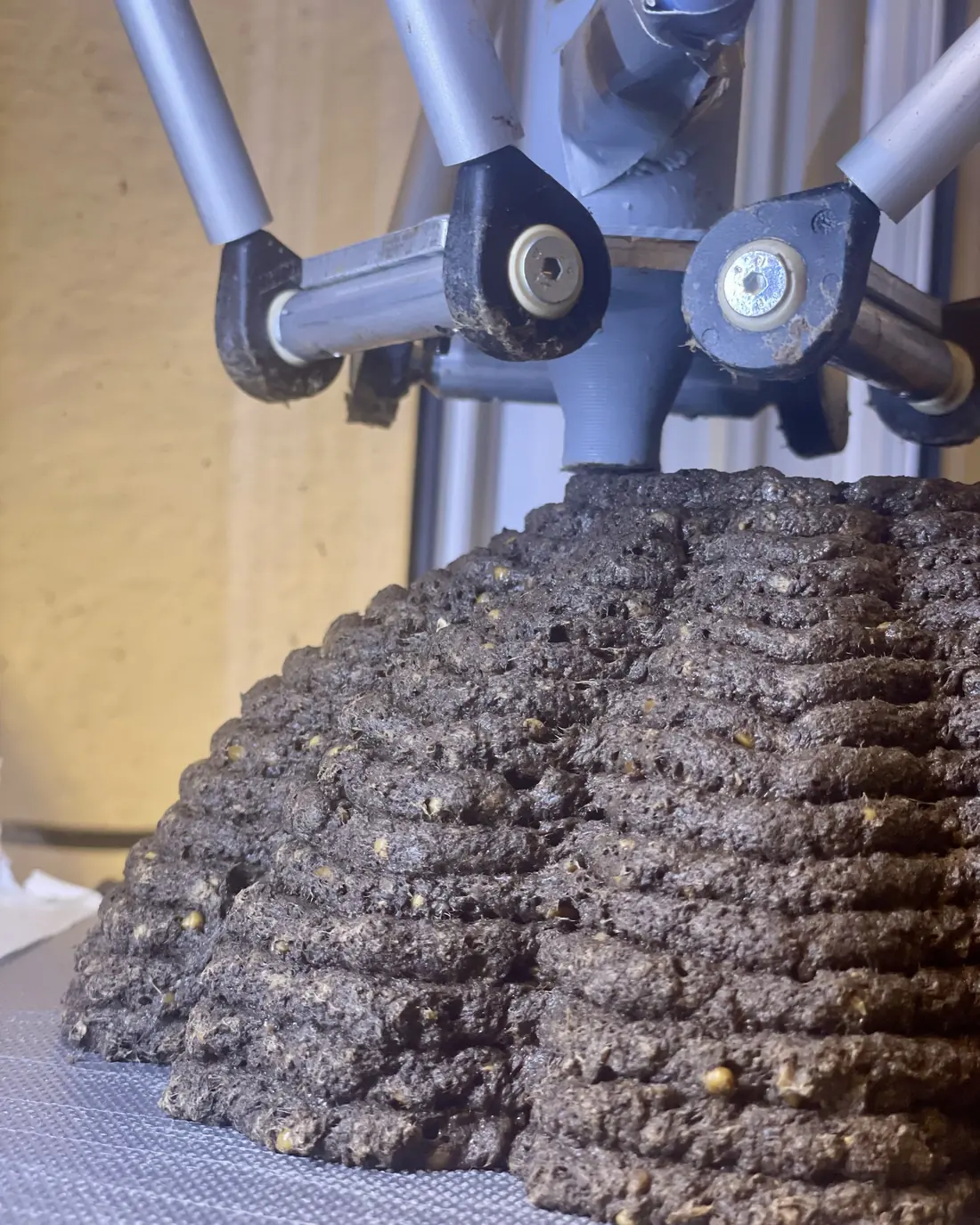 A delta printer extruding a grey mycelium paste