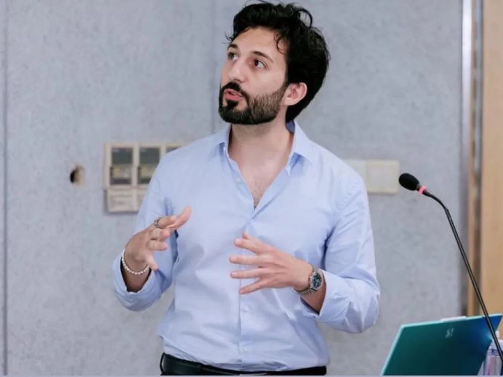 Raffaele presenting at Tongji University, gesturing as he speaks, a microphone beside him