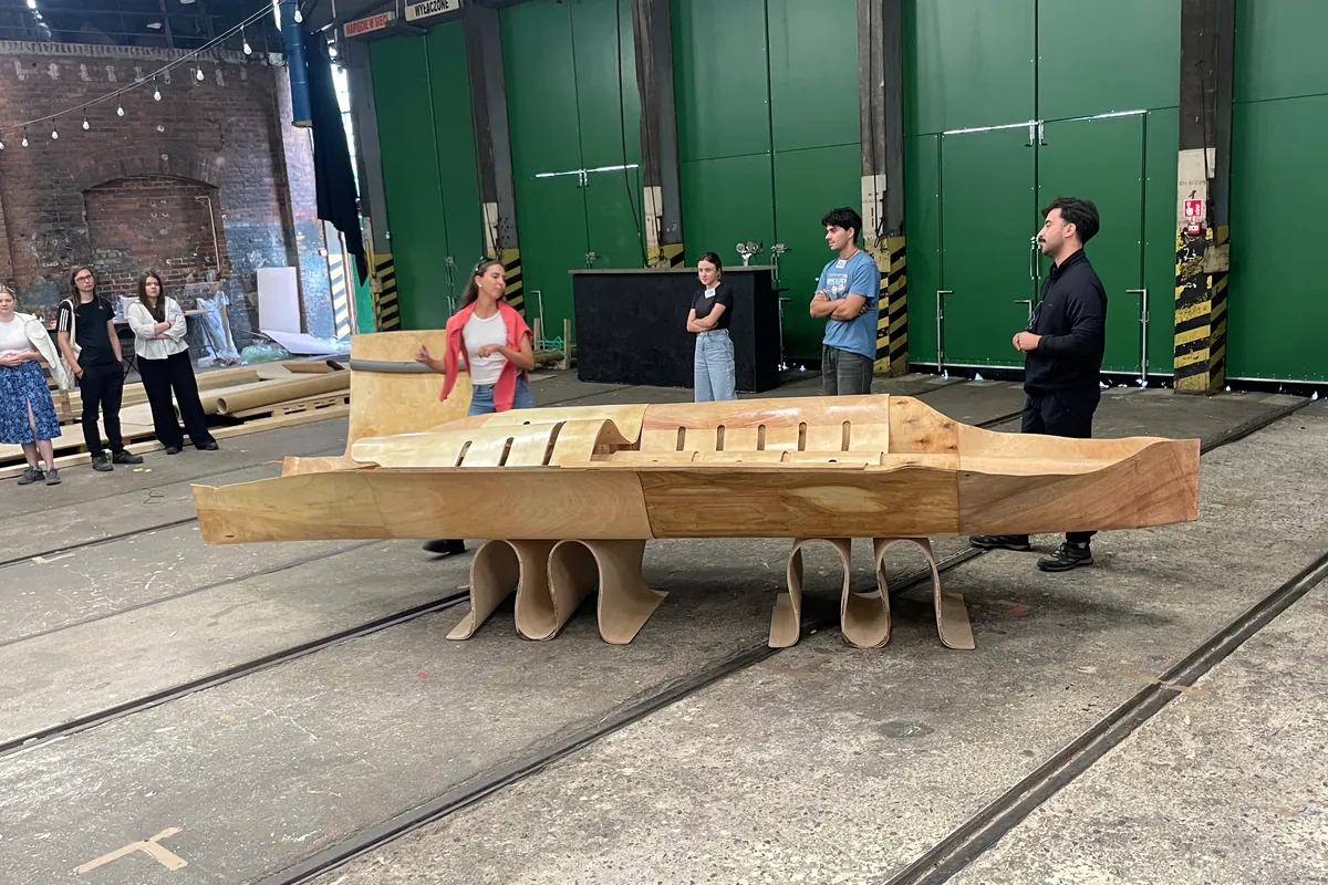 The canoe group presenting the finished hull to visitors in the hall, with their tutors