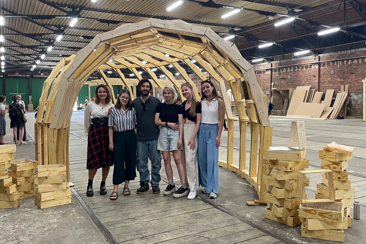Raffaele with his group of students in front of the finished timber vault, the bee boxes stacked beside it