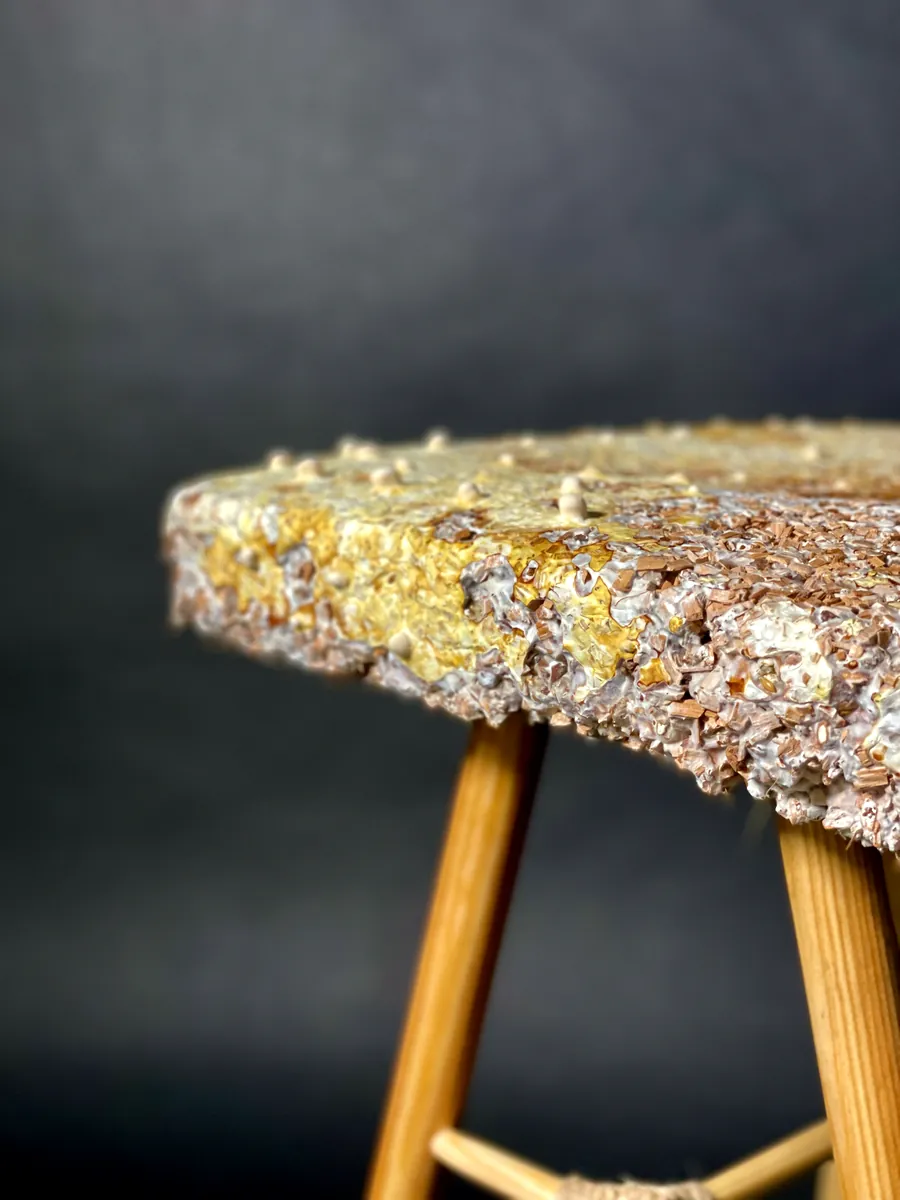 The edge of the seat on its turned leg, close